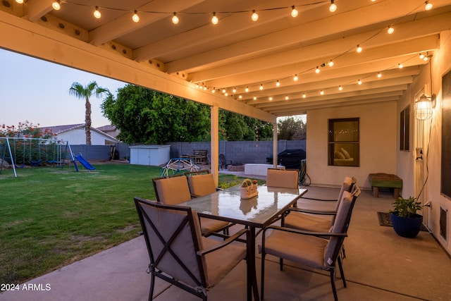 patio terrace at dusk with a shed, a playground, and a yard