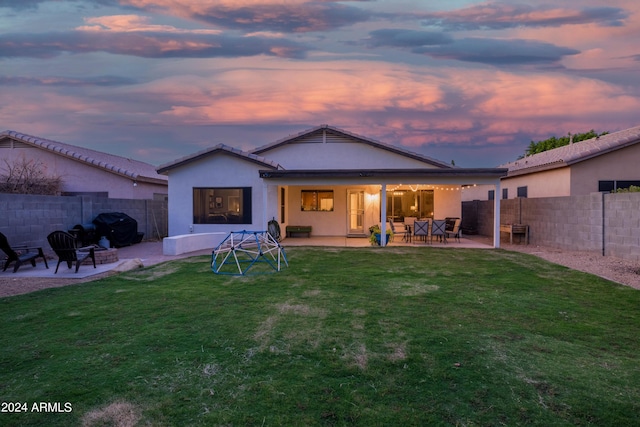 back house at dusk with a yard and a patio