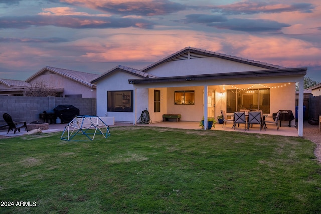 back house at dusk featuring a yard, a fire pit, and a patio area