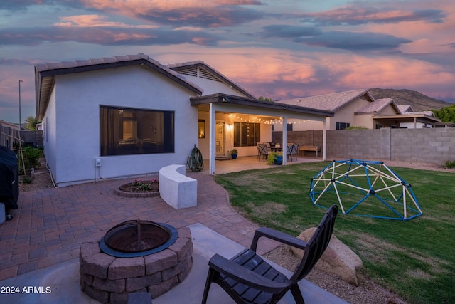 back house at dusk with a yard, a patio, and a fire pit