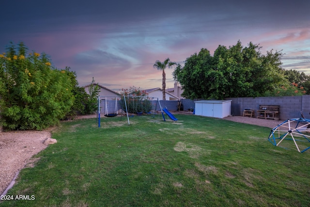 yard at dusk featuring a playground and a shed