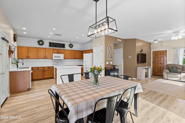 dining room featuring ceiling fan, sink, and light hardwood / wood-style flooring