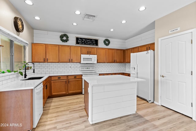 kitchen with sink, a kitchen island, white appliances, and light hardwood / wood-style flooring