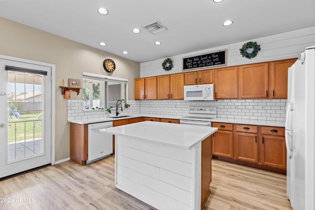 kitchen with sink, tasteful backsplash, light hardwood / wood-style floors, white appliances, and a kitchen island