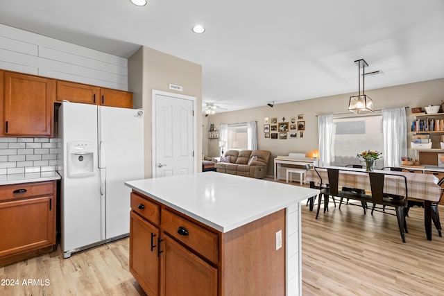 kitchen featuring backsplash, ceiling fan, white fridge with ice dispenser, decorative light fixtures, and a kitchen island