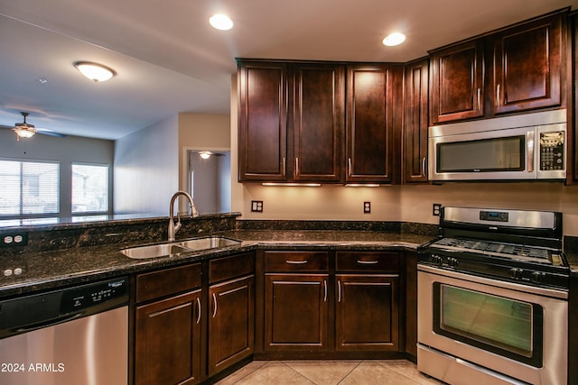 kitchen with ceiling fan, sink, dark stone countertops, light tile patterned floors, and appliances with stainless steel finishes