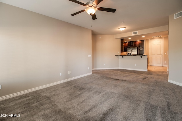 unfurnished living room featuring light carpet and ceiling fan