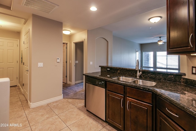 kitchen with stainless steel dishwasher, ceiling fan, dark stone counters, and sink