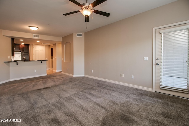 unfurnished living room featuring carpet and ceiling fan