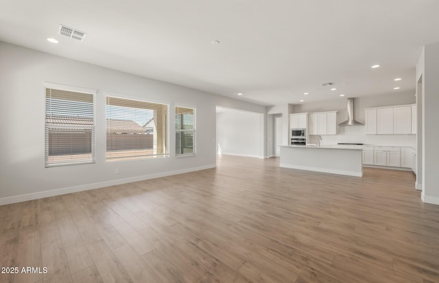 22660 E Pegasus Pkwy, Queen Creek, AZ 85142 - unfurnished living room featuring light wood-style floors, recessed lighting, a sink, and baseboards
