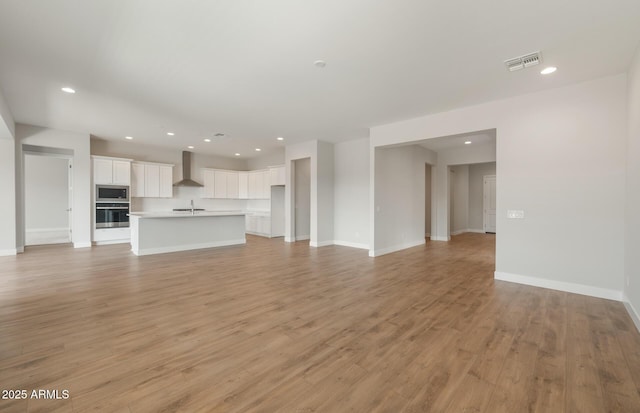 22660 E Pegasus Pkwy, Queen Creek, AZ 85142 - unfurnished living room with light wood-type flooring, a sink, baseboards, and recessed lighting