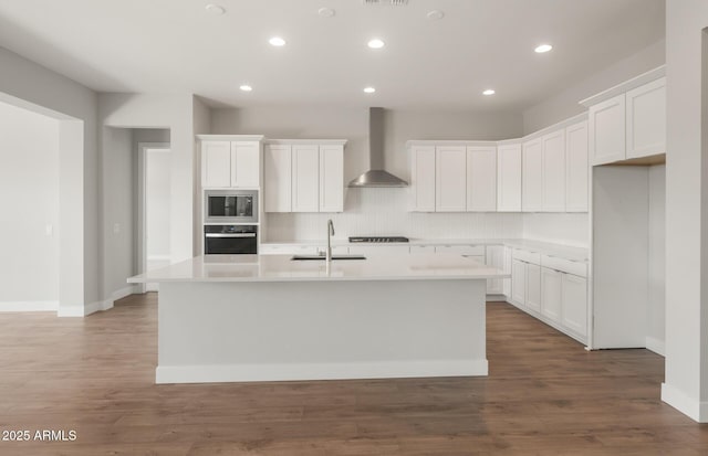 22660 E Pegasus Pkwy, Queen Creek, AZ 85142 - kitchen with wall chimney exhaust hood, built in microwave, oven, an island with sink, and stovetop