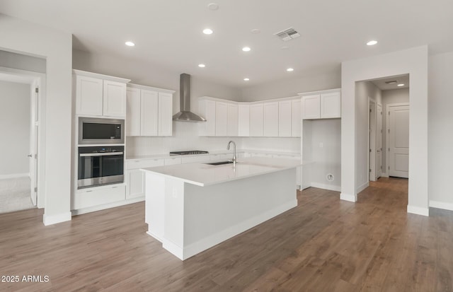 22660 E Pegasus Pkwy, Queen Creek, AZ 85142 - kitchen with stainless steel appliances, wall chimney exhaust hood, a sink, a kitchen island with sink, and white cabinets
