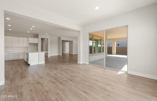 22660 E Pegasus Pkwy, Queen Creek, AZ 85142 - unfurnished living room featuring a sink, light wood-type flooring, recessed lighting, and baseboards