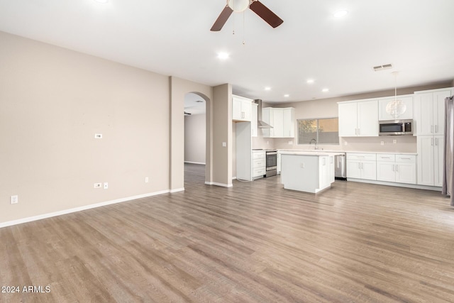 20293 N 83rd Dr, Peoria, AZ 85382 - kitchen with a ceiling fan, open floor plan, light wood-type flooring, arched walkways, and stainless steel appliances