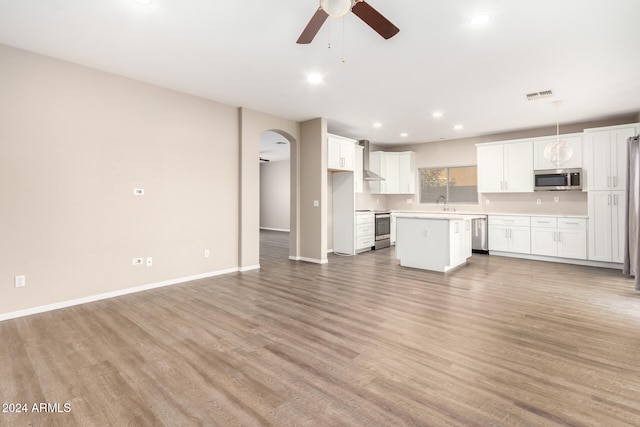 kitchen with light hardwood / wood-style floors, appliances with stainless steel finishes, a kitchen island, and hanging light fixtures