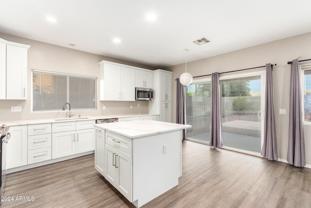 kitchen featuring white cabinets, light hardwood / wood-style flooring, sink, pendant lighting, and a center island