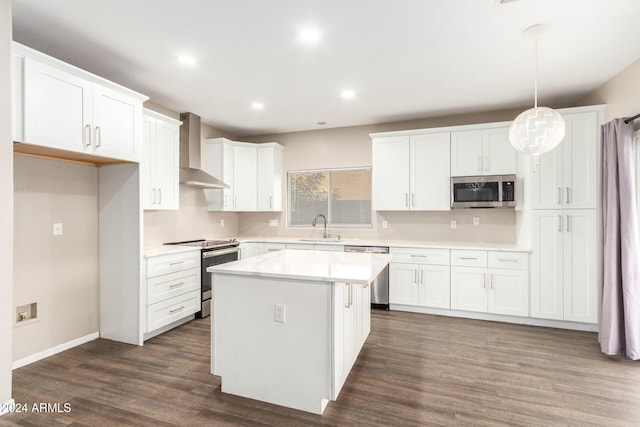 kitchen with appliances with stainless steel finishes, wall chimney range hood, and white cabinetry