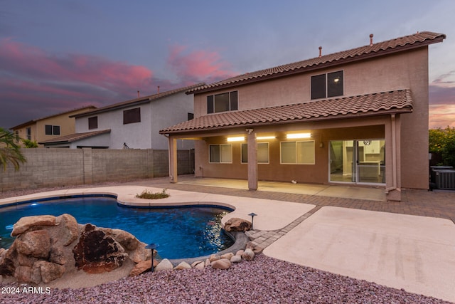 pool at dusk with central AC and a patio area