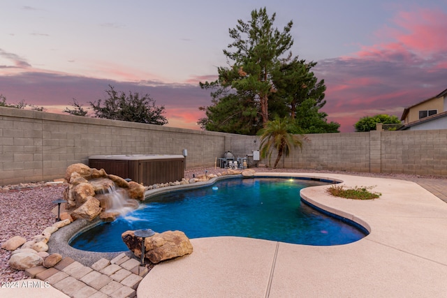 pool at dusk featuring a patio and pool water feature