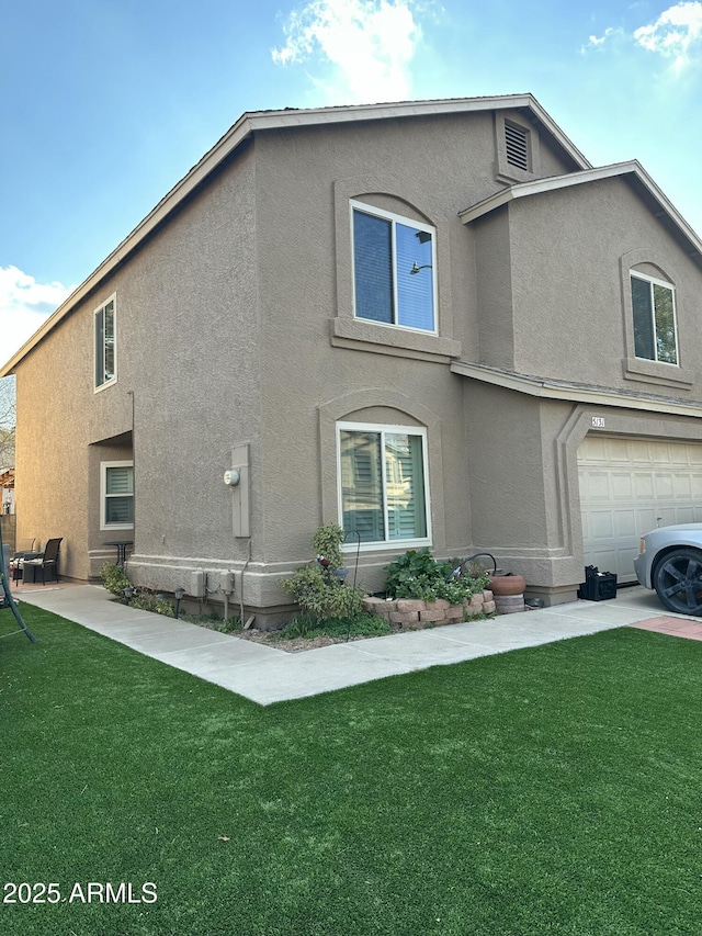 view of side of home featuring a garage, a yard, and stucco siding