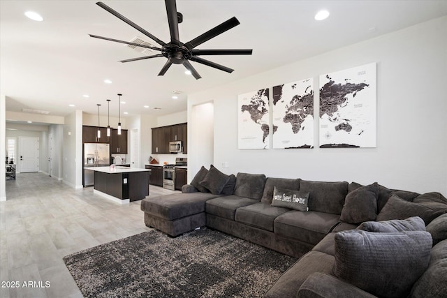 living room featuring light wood-type flooring, sink, and ceiling fan