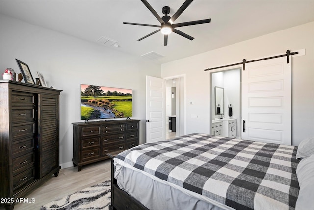 bedroom featuring ceiling fan, light hardwood / wood-style floors, and a barn door