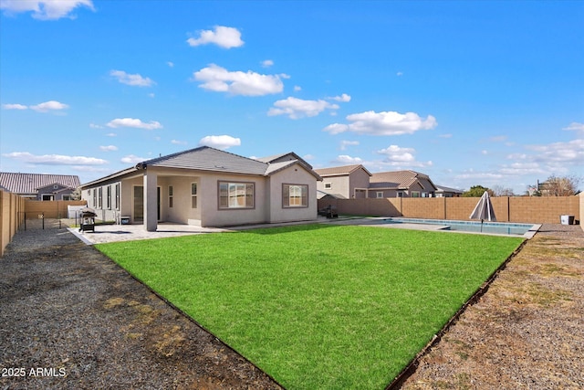 rear view of house with a patio area, a yard, and a fenced in pool