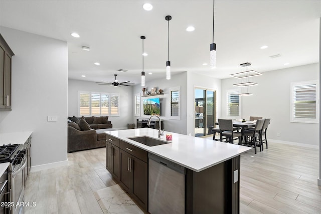 kitchen featuring appliances with stainless steel finishes, sink, hanging light fixtures, an island with sink, and dark brown cabinets