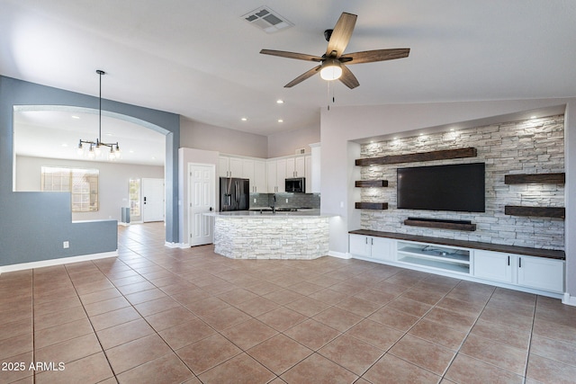 unfurnished living room featuring vaulted ceiling, sink, ceiling fan with notable chandelier, and light tile patterned floors