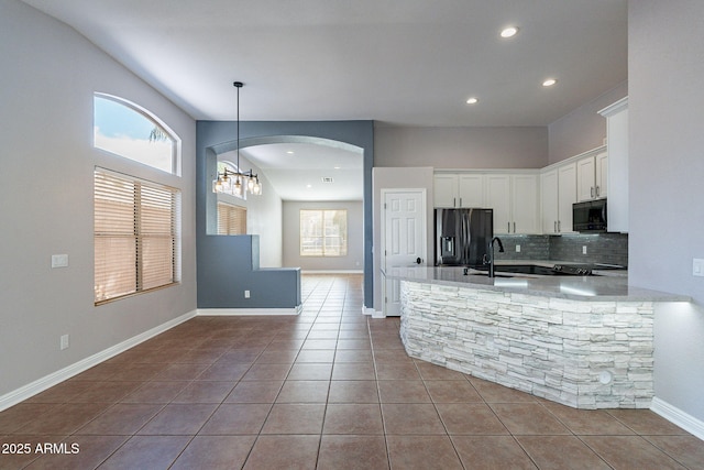 kitchen with sink, white cabinetry, stainless steel refrigerator with ice dispenser, decorative backsplash, and tile patterned floors