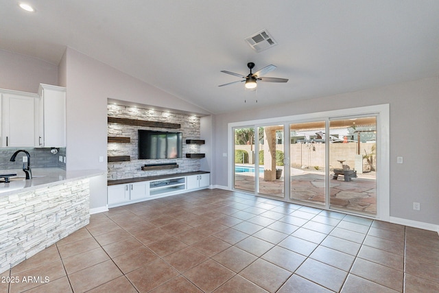 unfurnished living room featuring light tile patterned floors, vaulted ceiling, sink, and ceiling fan