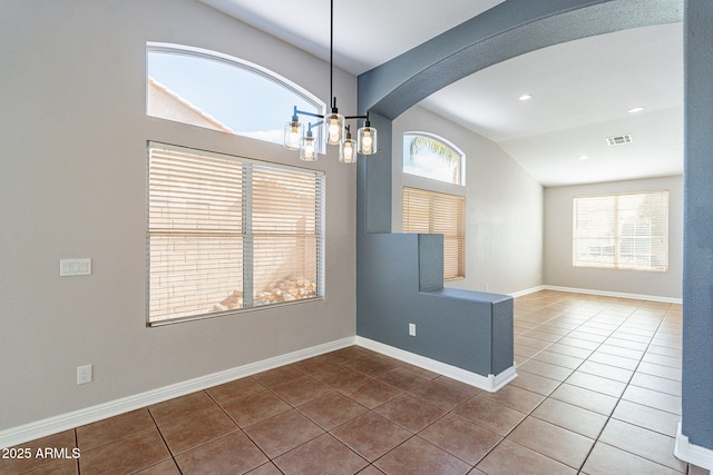 tiled spare room featuring a chandelier, vaulted ceiling, and a wealth of natural light