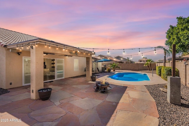 pool at dusk with a fire pit and a patio