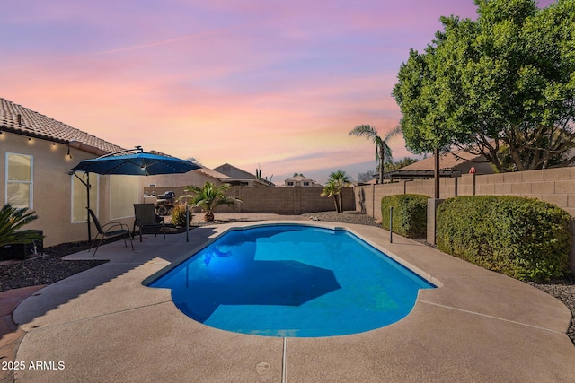 pool at dusk with a patio area