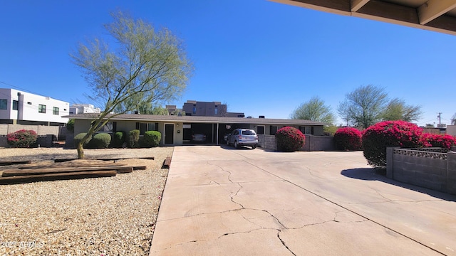 view of front facade featuring a carport, fence, and concrete driveway