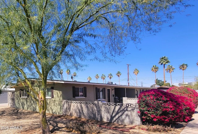 single story home featuring a sunroom and a fenced front yard