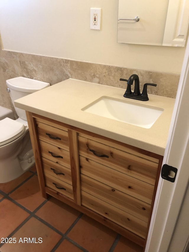 bathroom featuring tile walls, toilet, wainscoting, vanity, and tile patterned floors