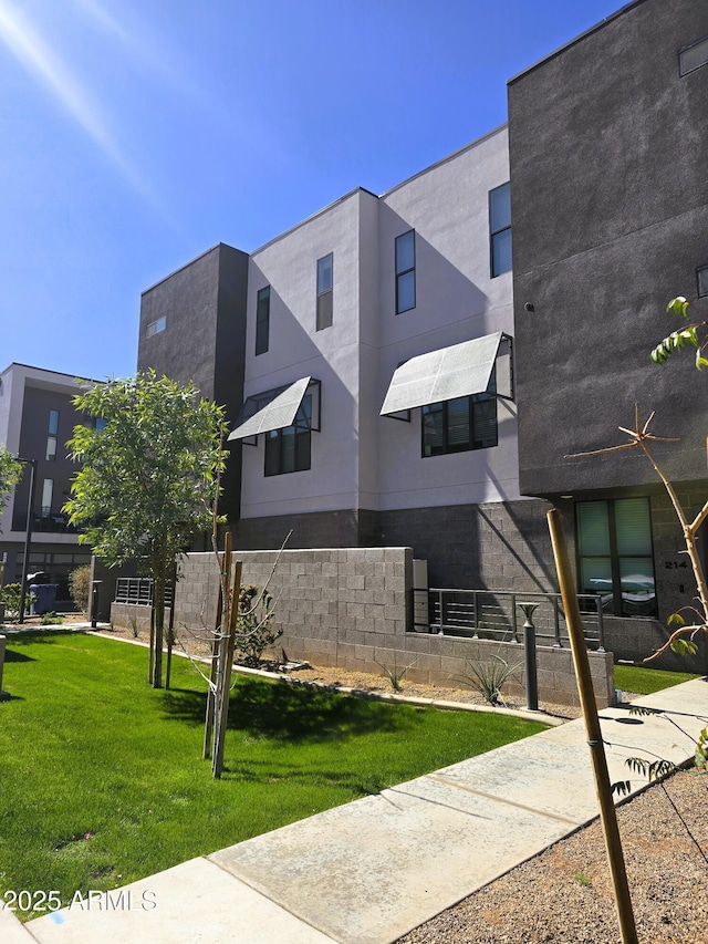 view of front of house featuring stucco siding, fence, and a front yard