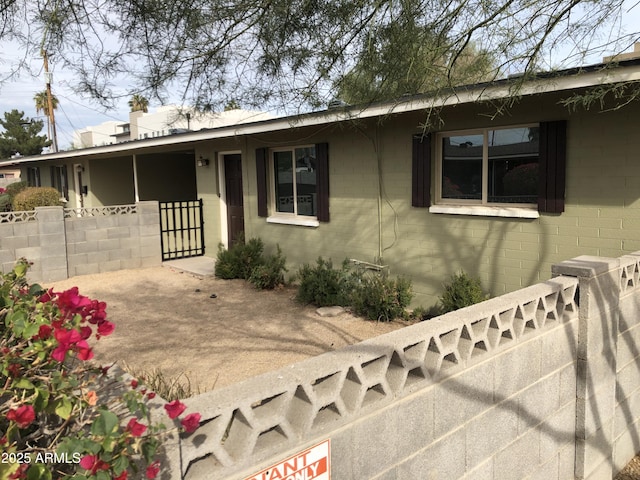 ranch-style home featuring concrete block siding and fence