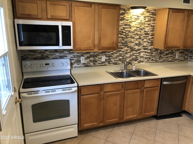 kitchen featuring appliances with stainless steel finishes, decorative backsplash, a sink, and light countertops