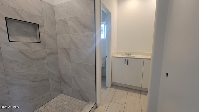 bathroom featuring vanity, toilet, and a tile shower