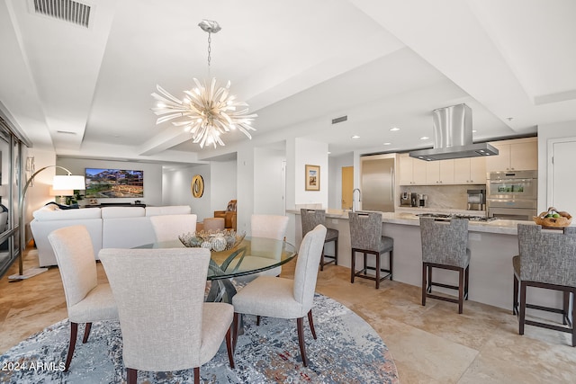 dining area featuring a tray ceiling, sink, and a chandelier