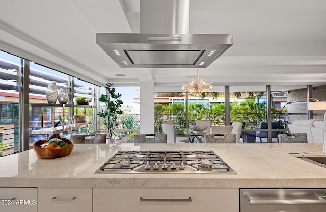 kitchen with white cabinets, light stone counters, stainless steel gas cooktop, and island exhaust hood