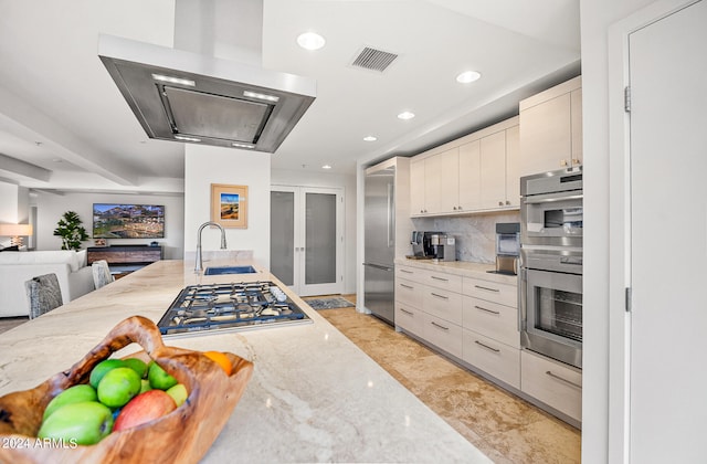 kitchen featuring ventilation hood, stainless steel appliances, light stone counters, and tasteful backsplash