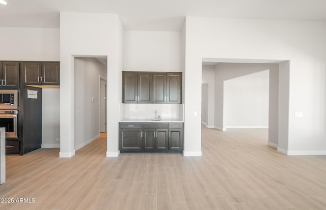 18716 N 269th Ln, Buckeye, AZ 85396 - kitchen featuring oven, light wood-style floors, built in microwave, dark brown cabinetry, and baseboards