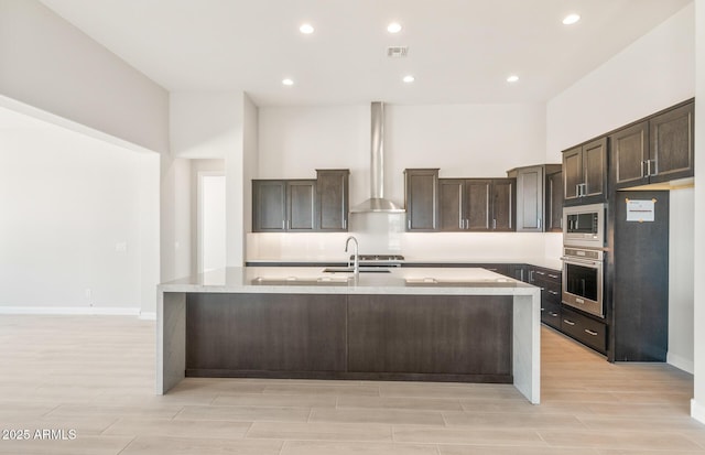 18716 N 269th Ln, Buckeye, AZ 85396 - kitchen with stainless steel appliances, wall chimney range hood, dark brown cabinets, light wood-style flooring, and light countertops