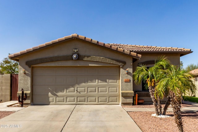 view of front of house featuring an attached garage, driveway, a tile roof, and stucco siding