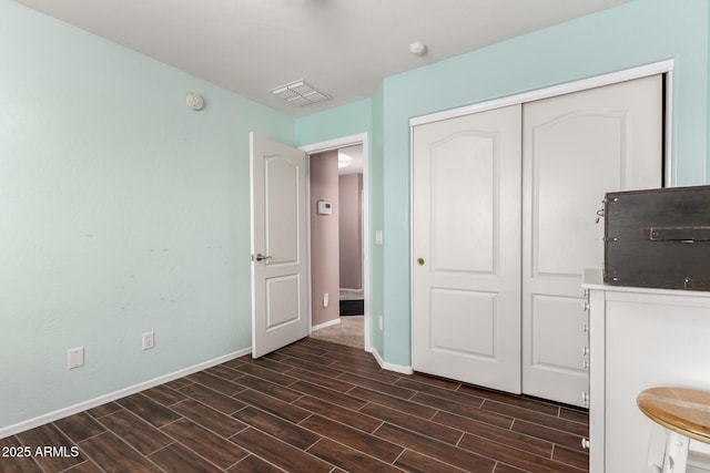 interior space with baseboards, wood tiled floor, visible vents, and a closet