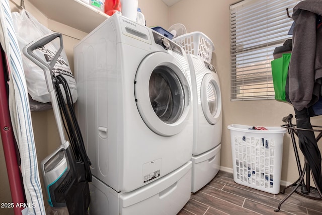 washroom featuring laundry area, washing machine and dryer, wood tiled floor, and baseboards